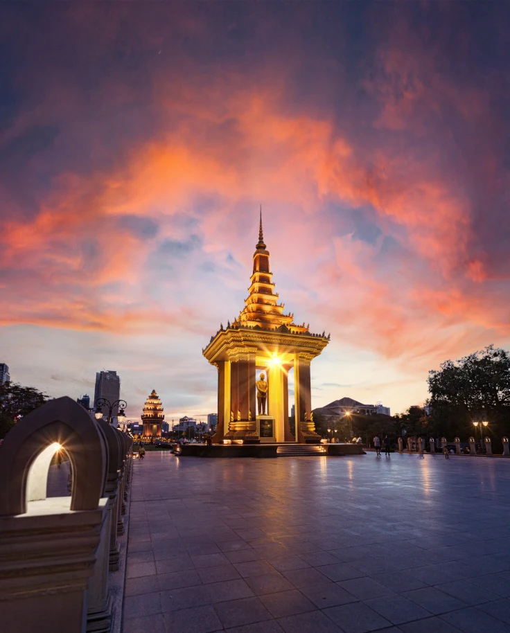 A golden temple lit up at night against a pink and blue sunset