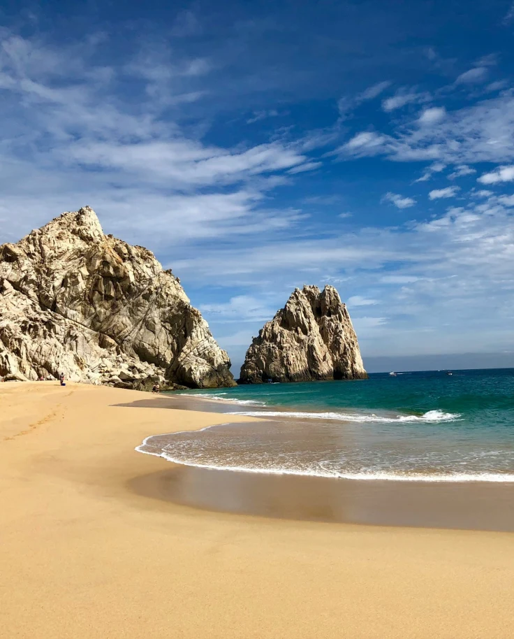 A picture of brown rock formation on seashore under the blue skies.