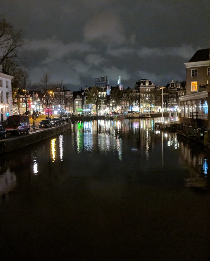 A lit-up Amsterdam on the river at night.