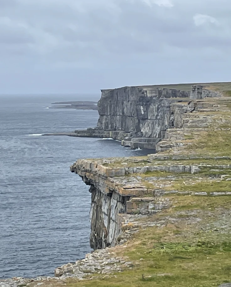Cliffs edge next to a body of water during a cloudy day