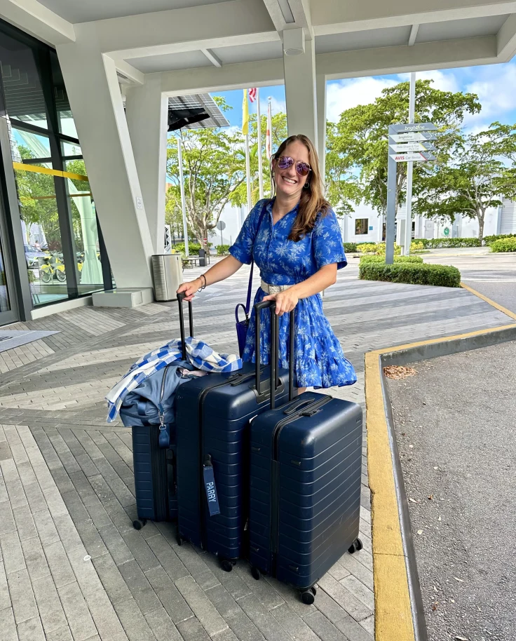 A woman standing with three suitcases.