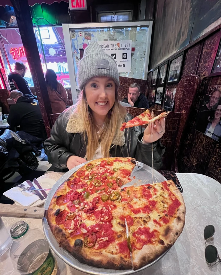 A woman getting a slice of pizza from the whole pizza.