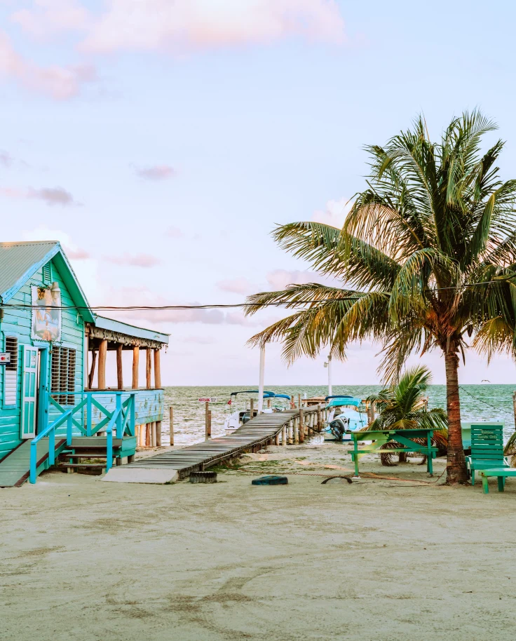 a staple of any belize itinerary: beautiful beach with palm trees next to a colorful building