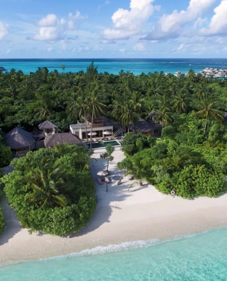 aerial view of villa on beach surrounded by trees during daytime