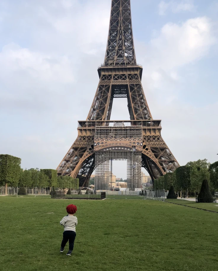 A kid running in front of Eiffel Tower.