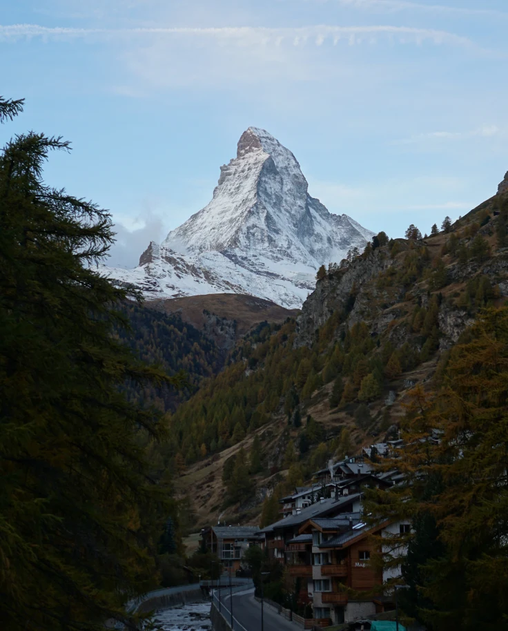 Large wooden mountain ski lodge in front of snowy alps in Switzerland.
