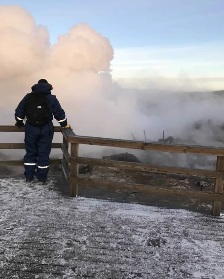 A person overlooking the smoke near a wooden fence outside.