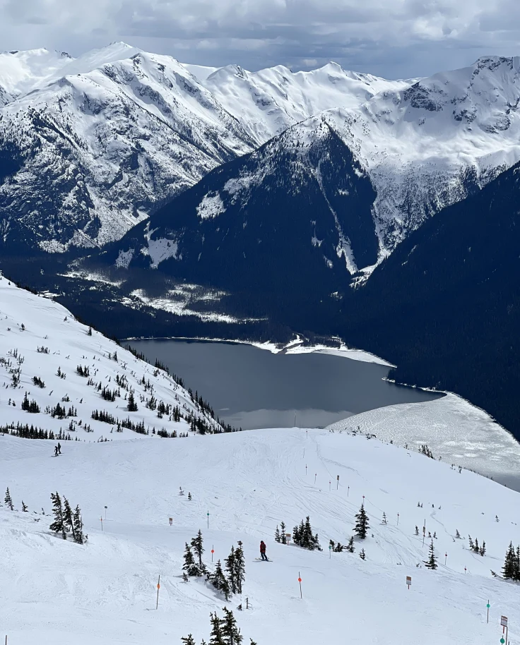 Snowy mountain with body of water during daytime