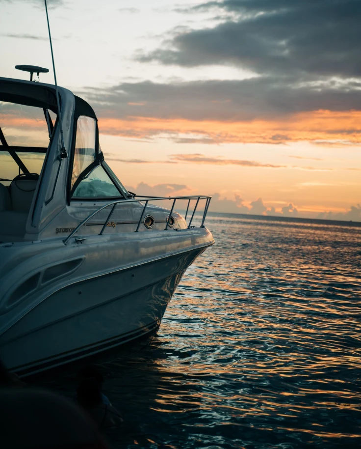 a speed boat floats on the open ocean at sunset