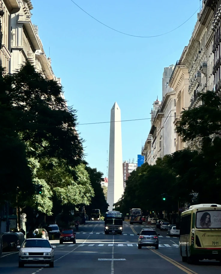 A road through a city street with a tall monument at the end during the daytime