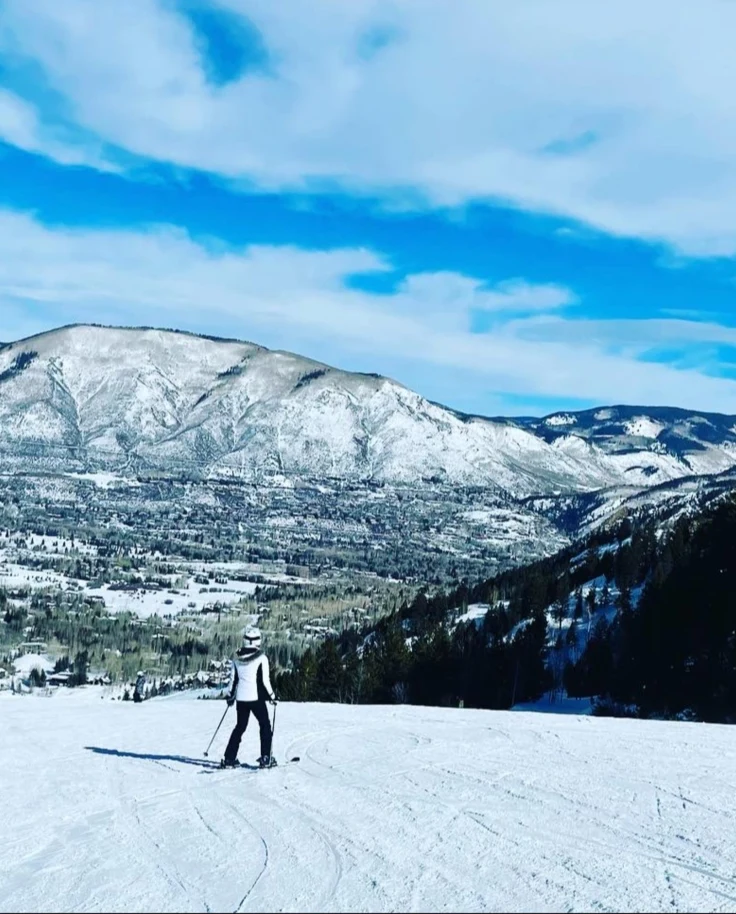 A girl standing on a snowy mountain during daytime.