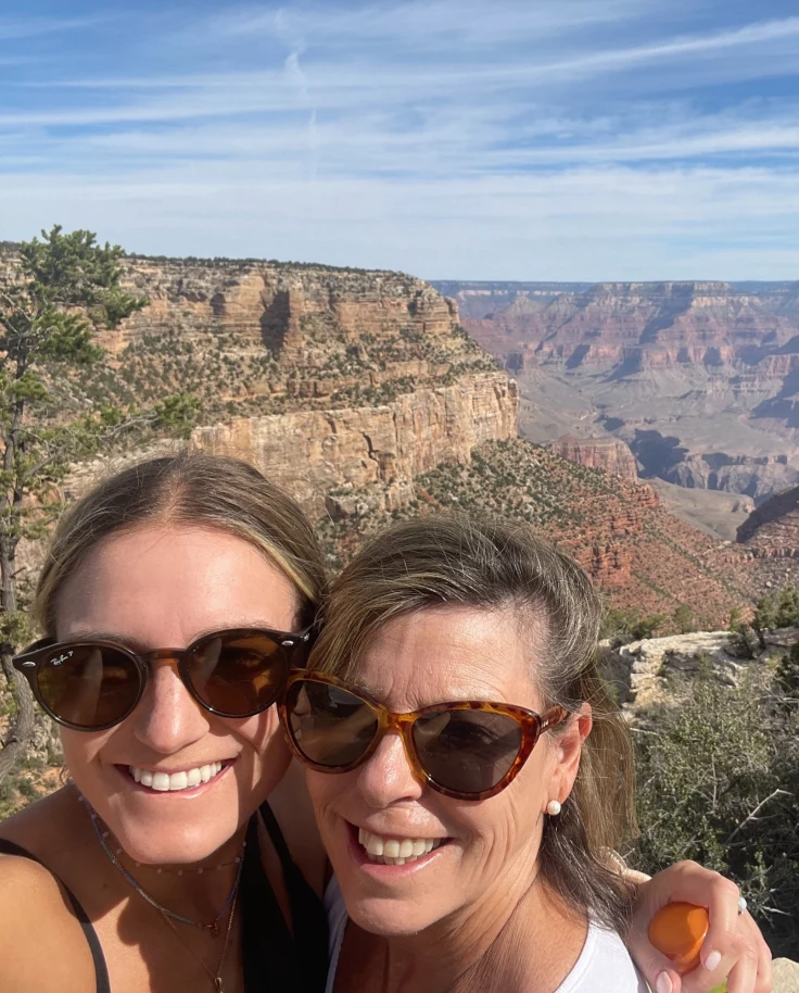 A selfie of two women hiking with canyons in the background.