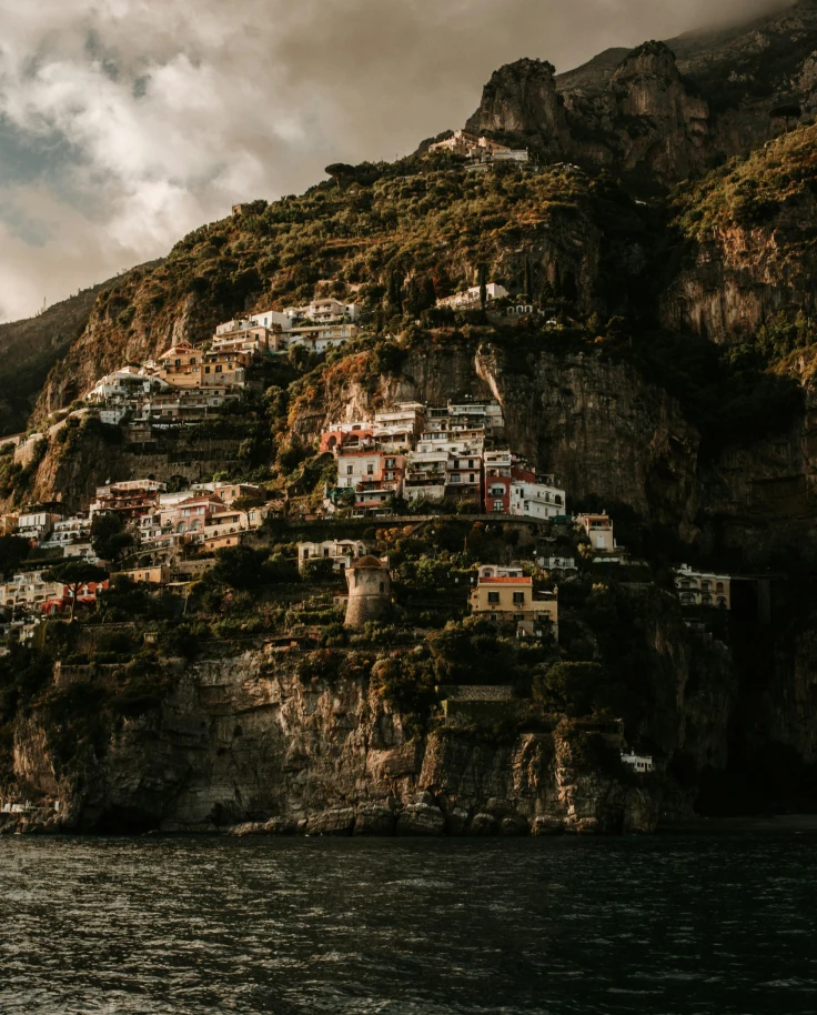 Houses on mountain near ocean on a cloudy day.