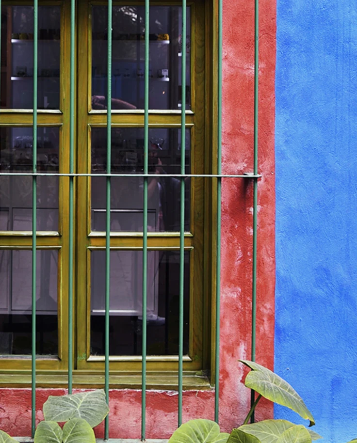 A large window with gold panes on a blue and red house