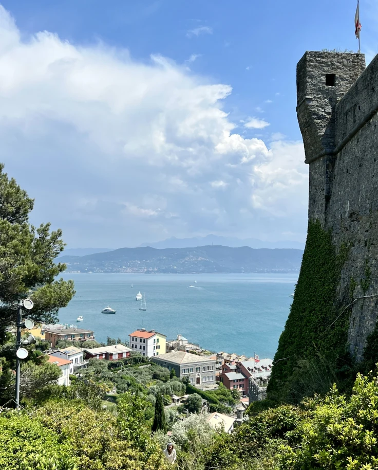 View of a castle, buildings with sea in the background.