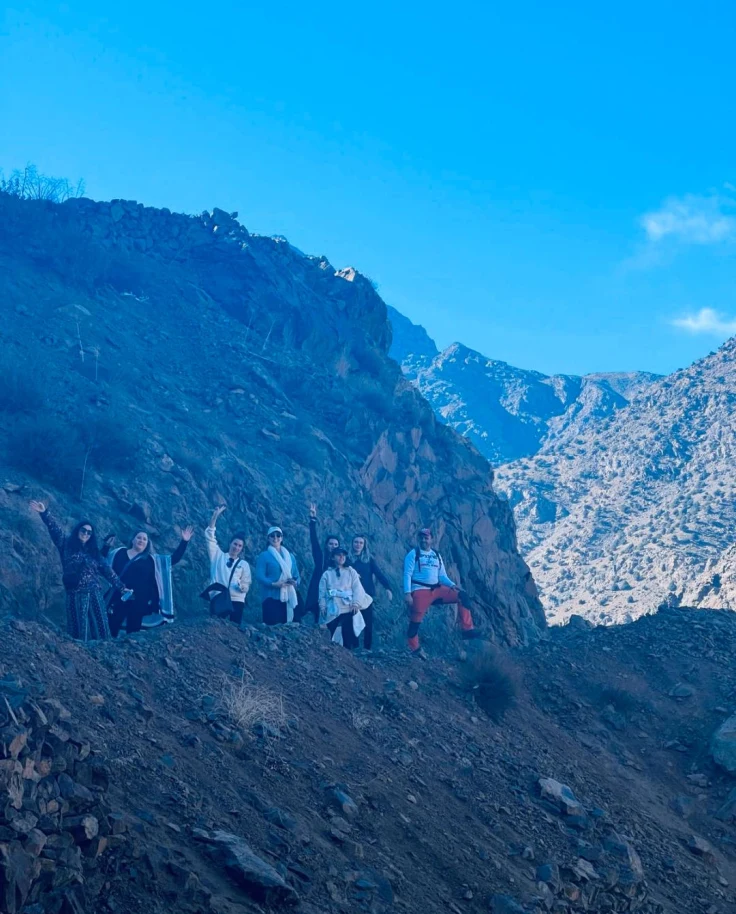 A group of people posing for a photo on the side of the Morocco Atlas Mountains during the daytime.
