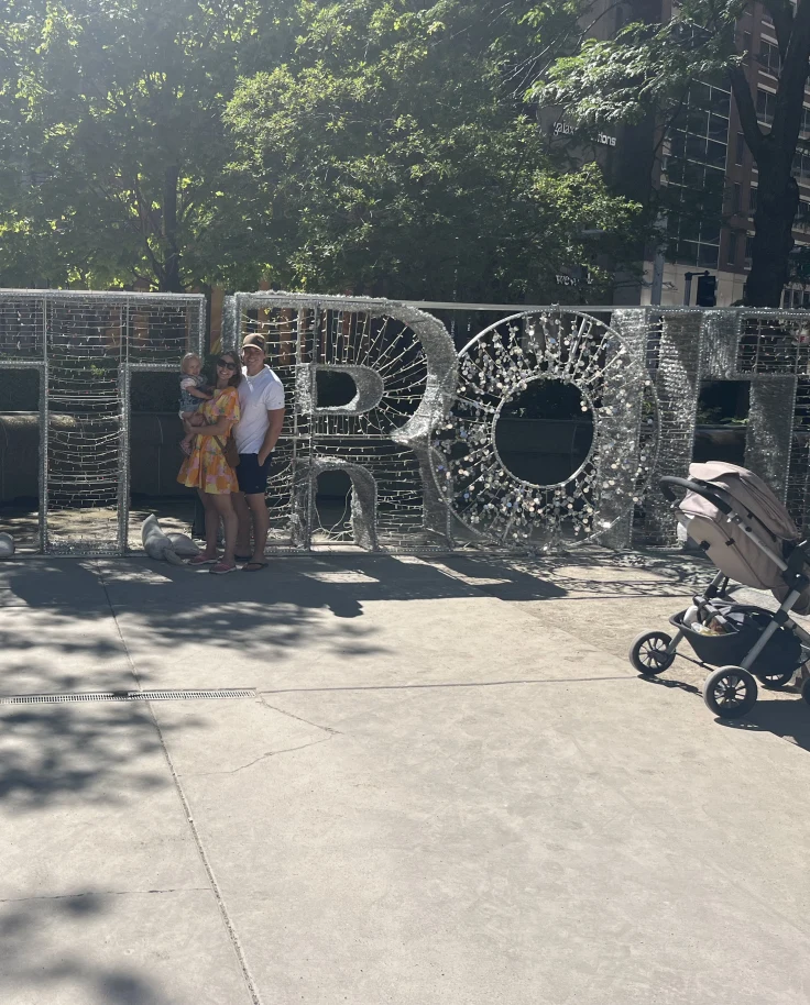 A picture of a man, woman and child standing in front of letters making up the word DETROIT