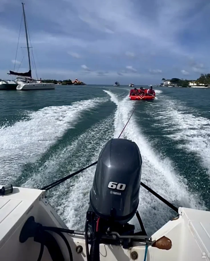 People enjoying a ride in a red rubber dinghy attached to a boat on the ocean