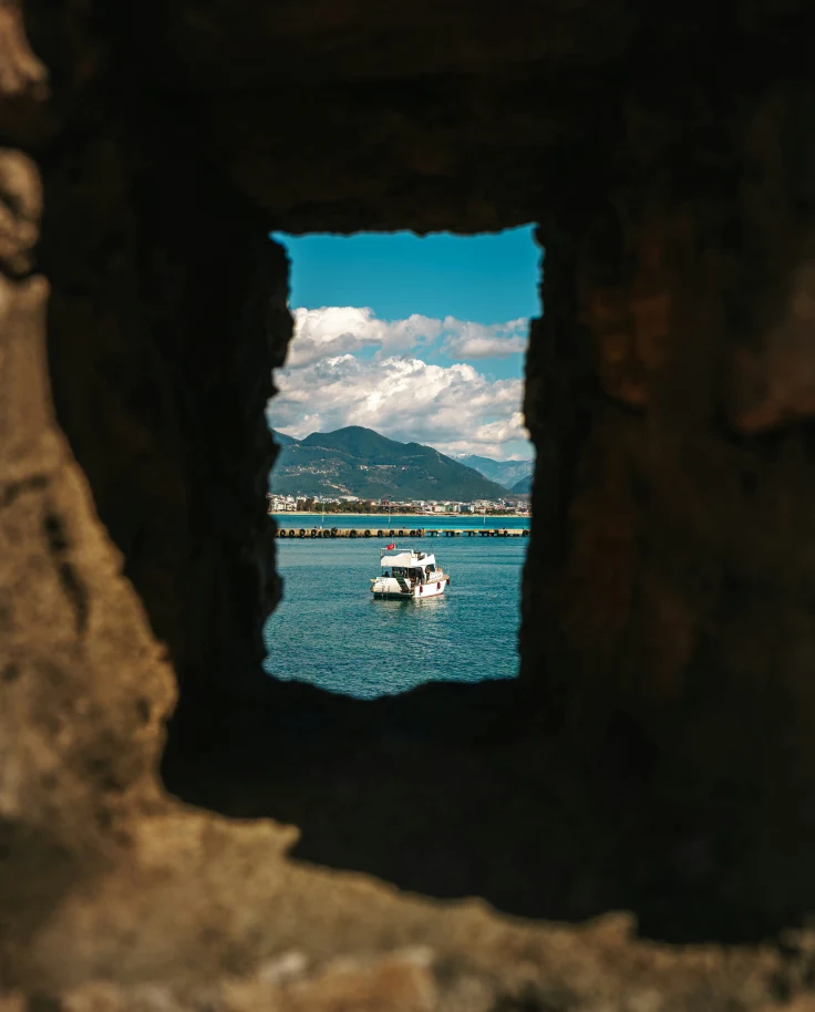 A boat on the water seen through a rock outcropping.