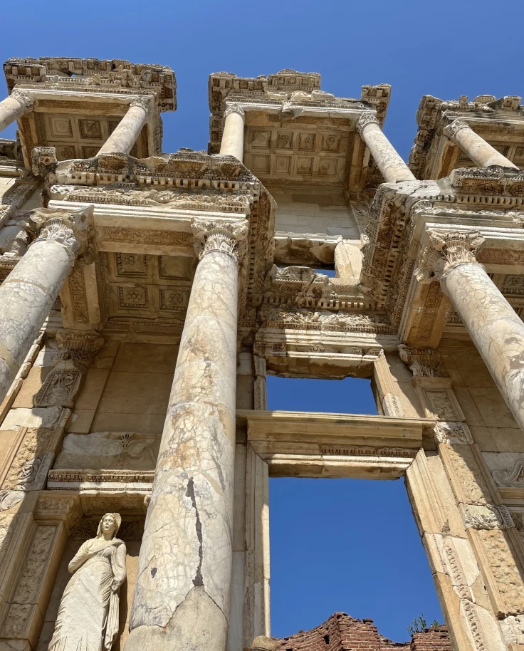 A bottom-up view of ancient stonework with the blue sky in the background.