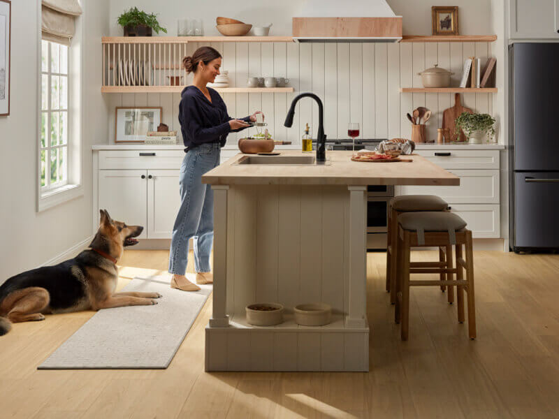 woman in kitchen with dog at her feet on wood-look, pet-friendly flooring