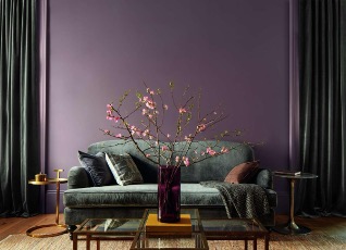 A purple living room with a couch and a vase of flowersDescription automatically generated