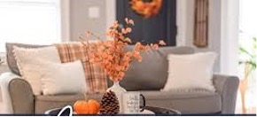 A vase with orange flowers and a mug on a tableDescription automatically generated