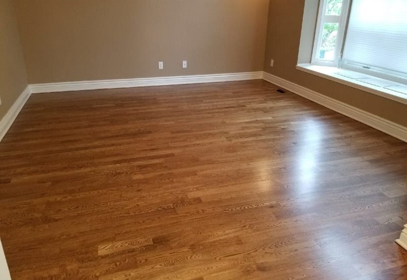Refinished hardwood floor in a St. Louis bedroom with natural light and neutral walls.
