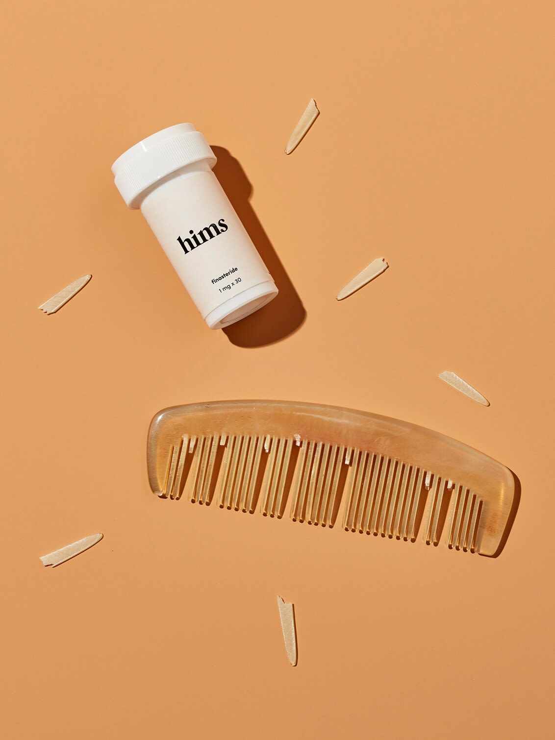 A bottle of Finasteride and a comb with its teeth falling out, scattered around