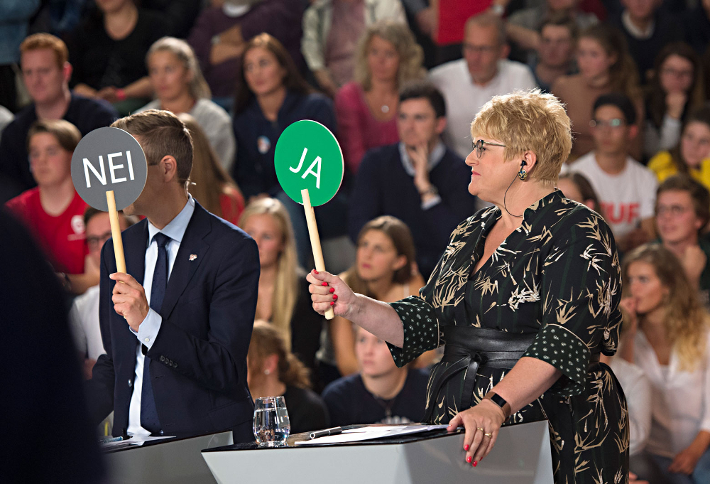 Foto fra TV-debatt med partiledere. Knut Arild Hareide fra Kristelig Folkeparti og Trine Skei Grande fra Venstre holder opp avstemmingsskilt med «JA» og «NEI».