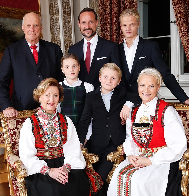 Portrettfoto av kongefamilien: Sonja og Harald, Haakon Magnus og Mette Marit, Ingrid Alexandra, Sverre Magnus og Marius. De er samlet på Skaugum til jul; Sonja og Mette Marit har bunad.