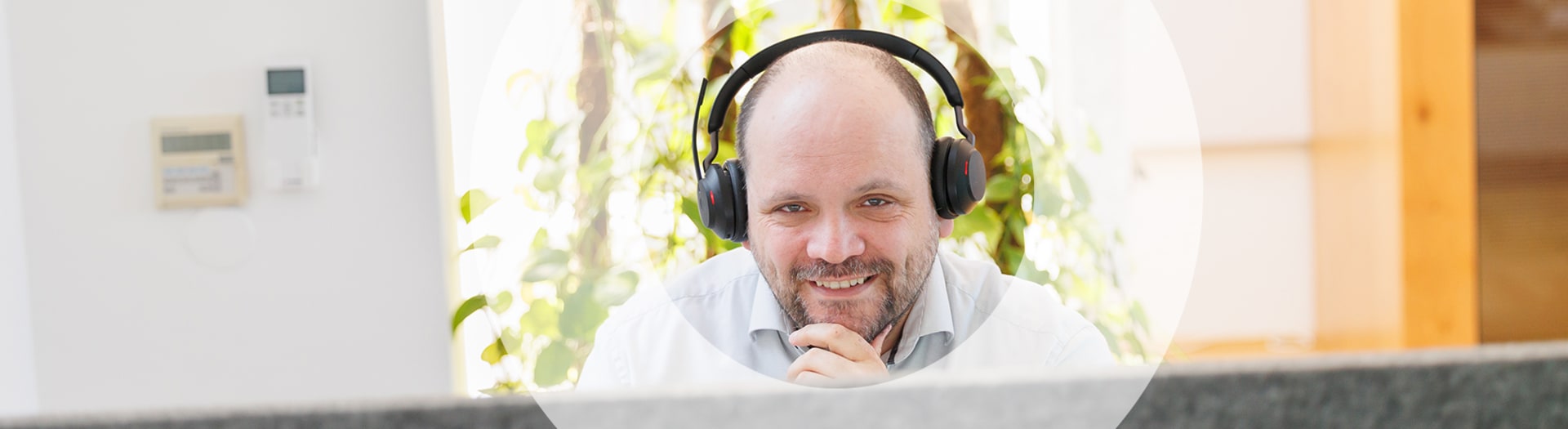 Mann mit Headset bei der Kundenberatung lächelt in die Kamera.