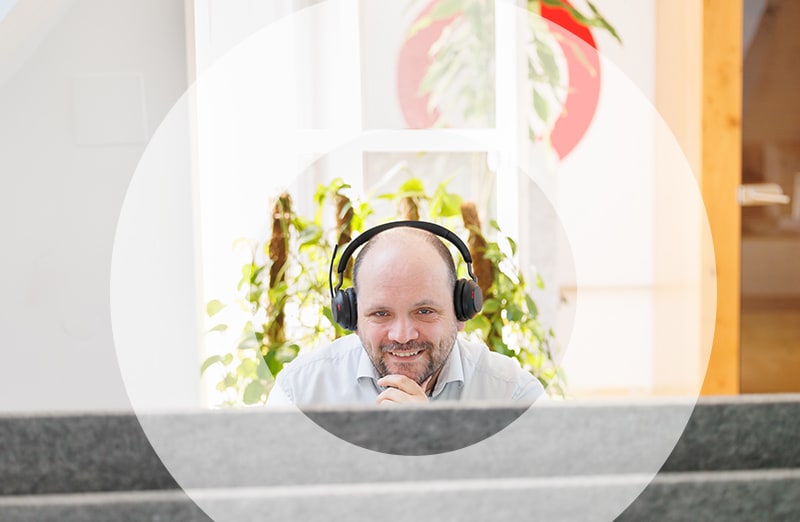 Mann mit Headset bei der Kundenberatung lächelt in die Kamera.