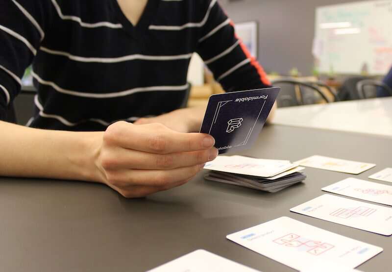 Individual drawing a card from a deck of Formidable UX cards