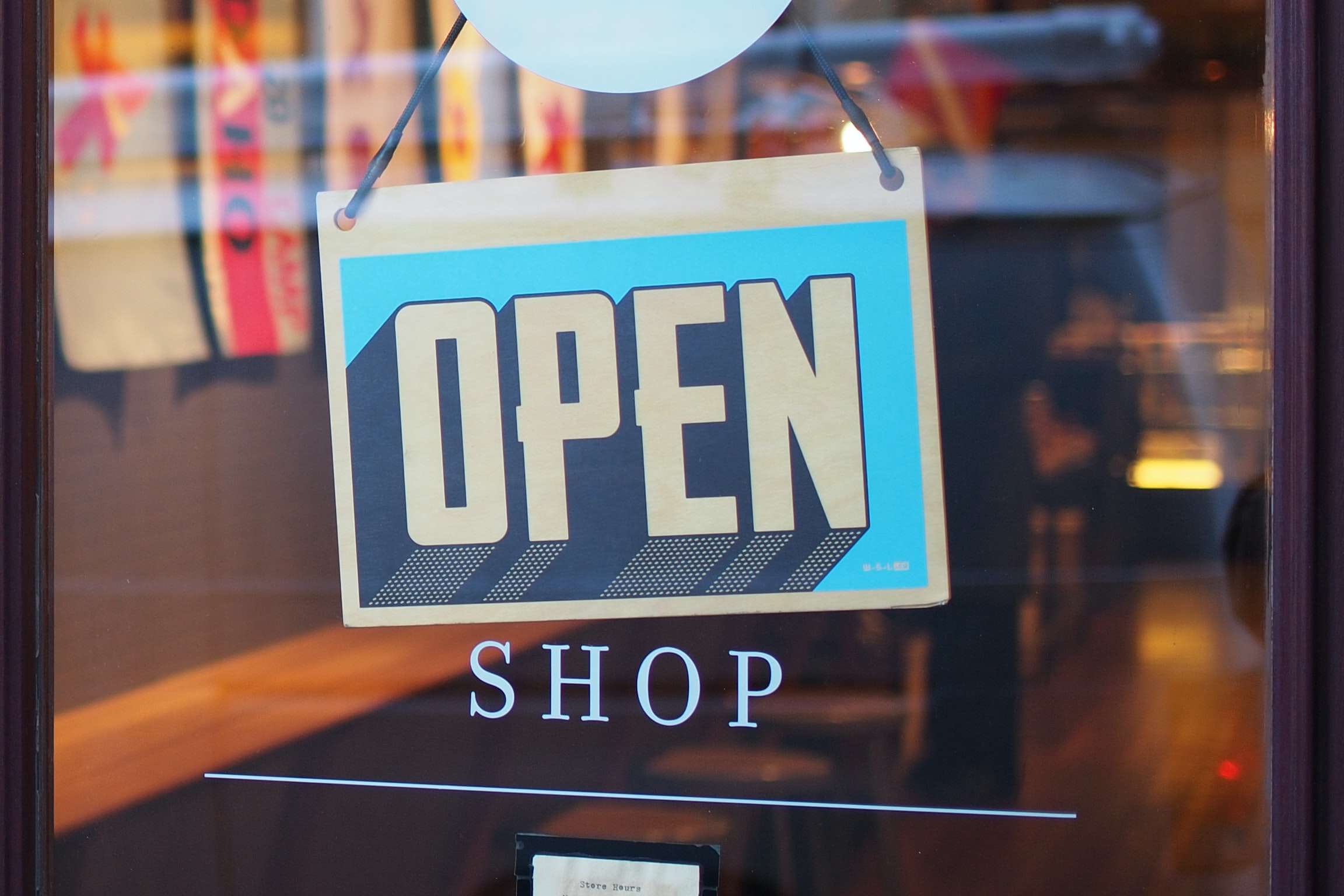 Photo by Mike Petrucci on Unsplash of a sign on a shop door that says open