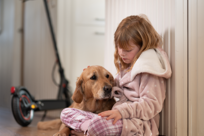Jente som sitter med hund og elsparkesykkel til lading
