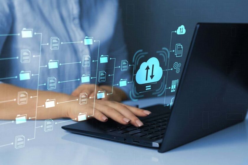 Person som skriver på en laptop. Teknologiske symboler over