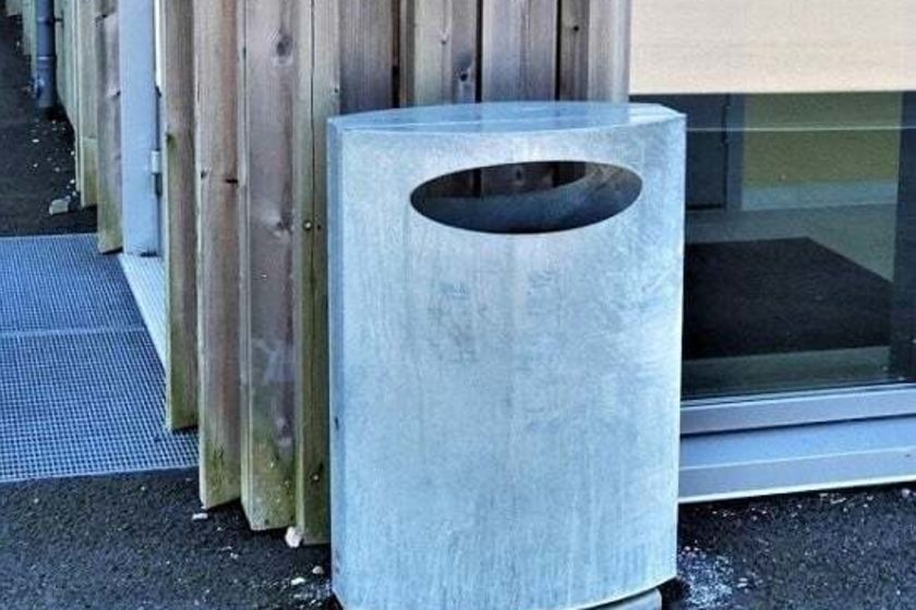 Søppelkasse plassert rett ved trevegg