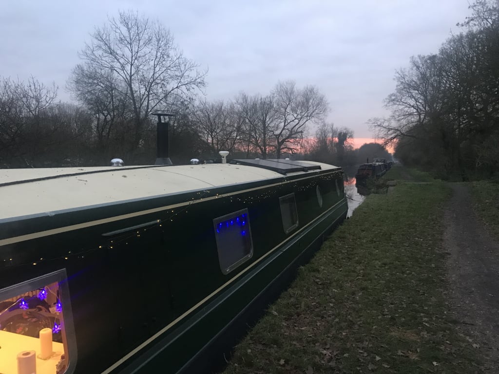 Widebeam canal boat with Christmas lights visible on the hull