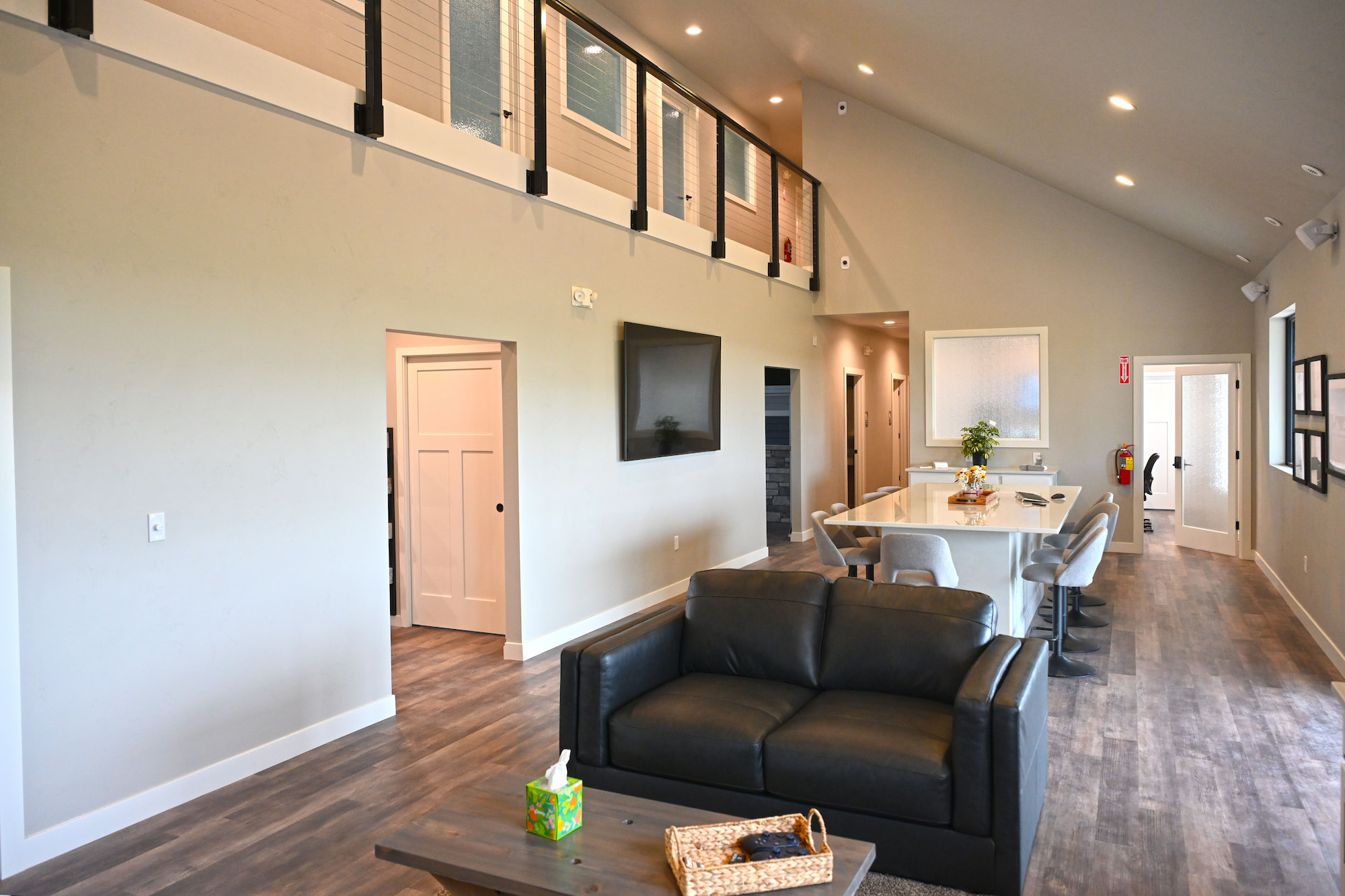 Open-concept commercial construction interior featuring a modern kitchen, meeting area with bar seating and leather couch