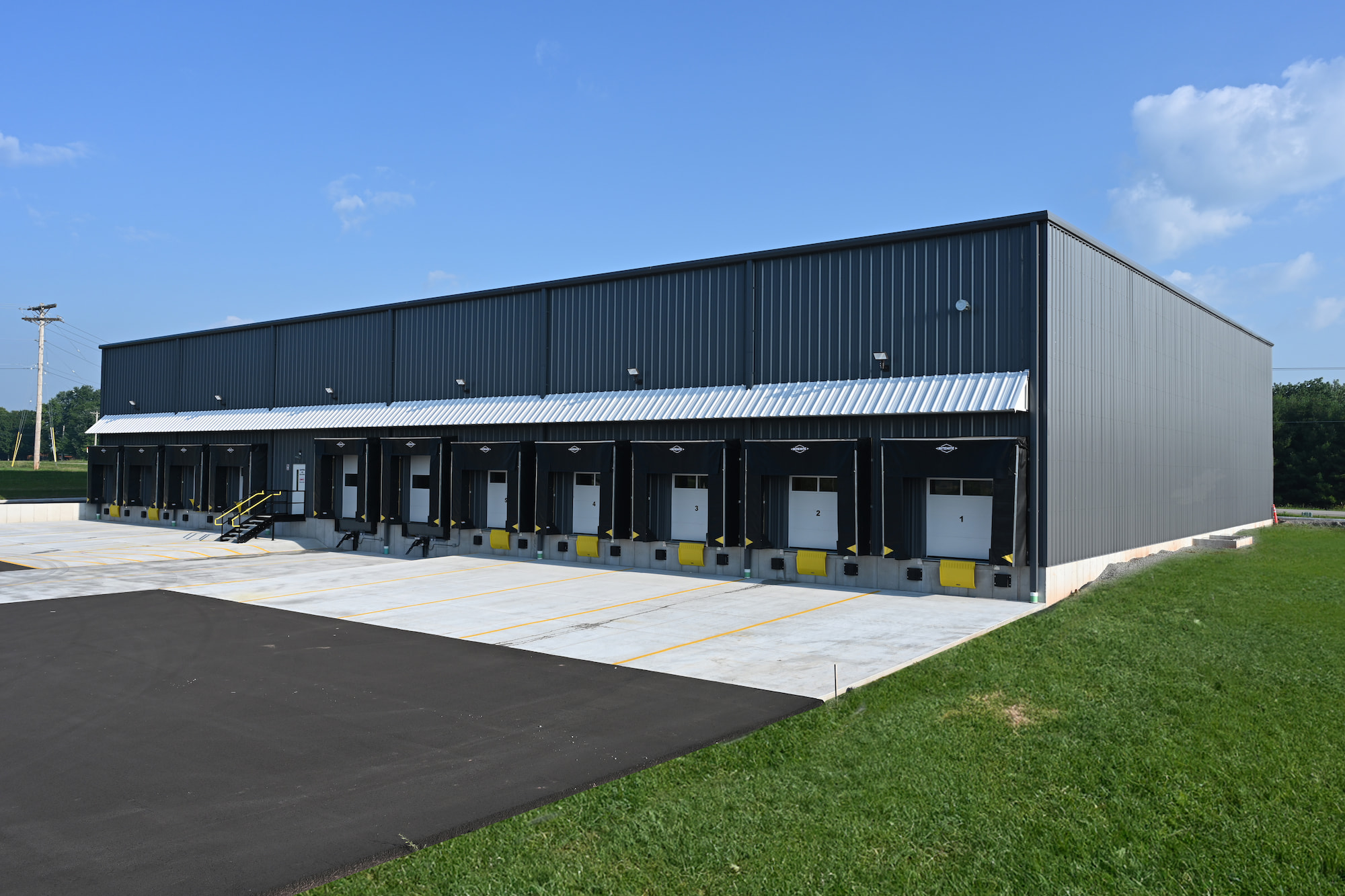 Rear view of commercial warehouse in Kaukauna, WI with multiple loading dock bays and concrete truck apron.