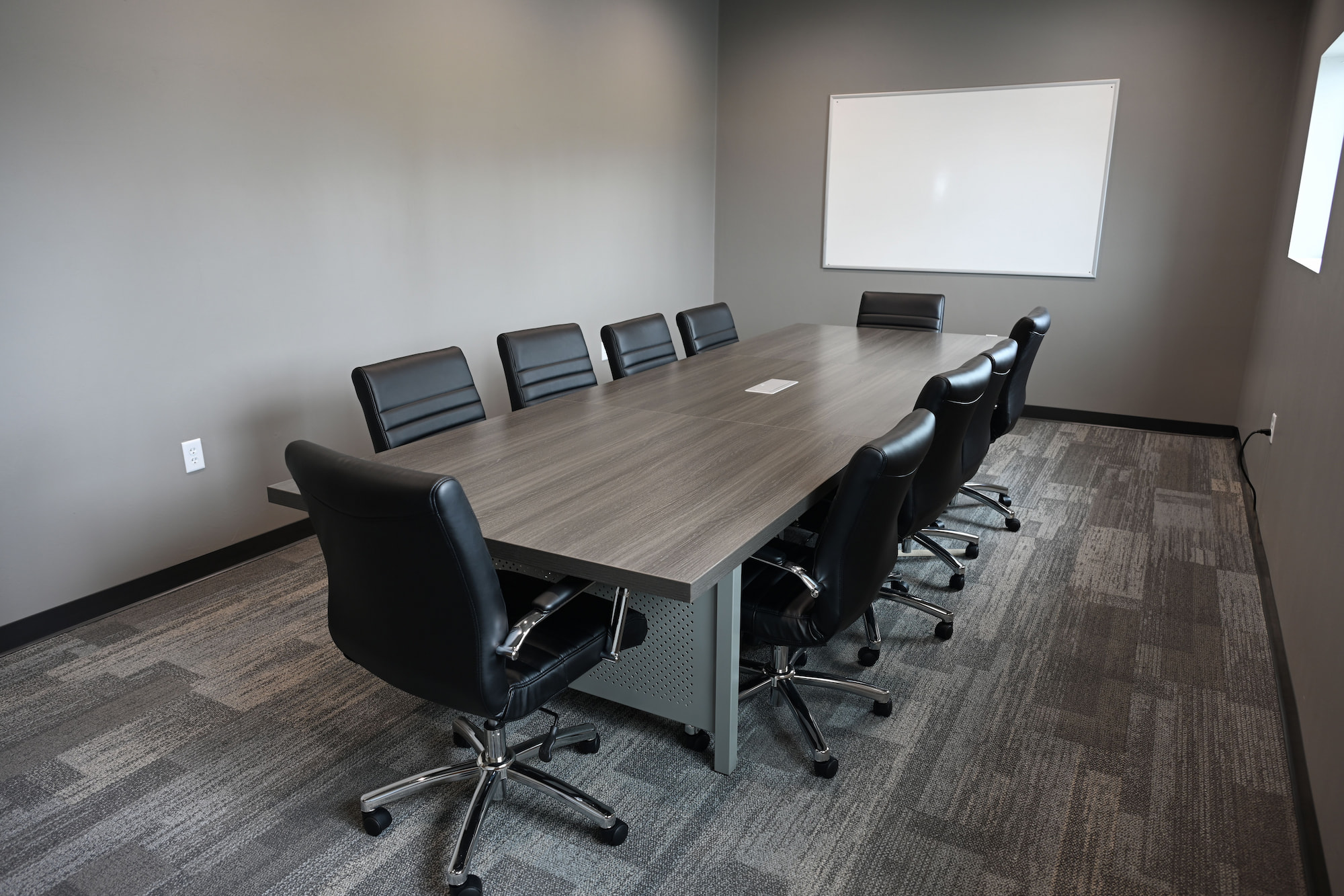 Modern conference room with long meeting table and leather chairs inside SkidSteers.com office.