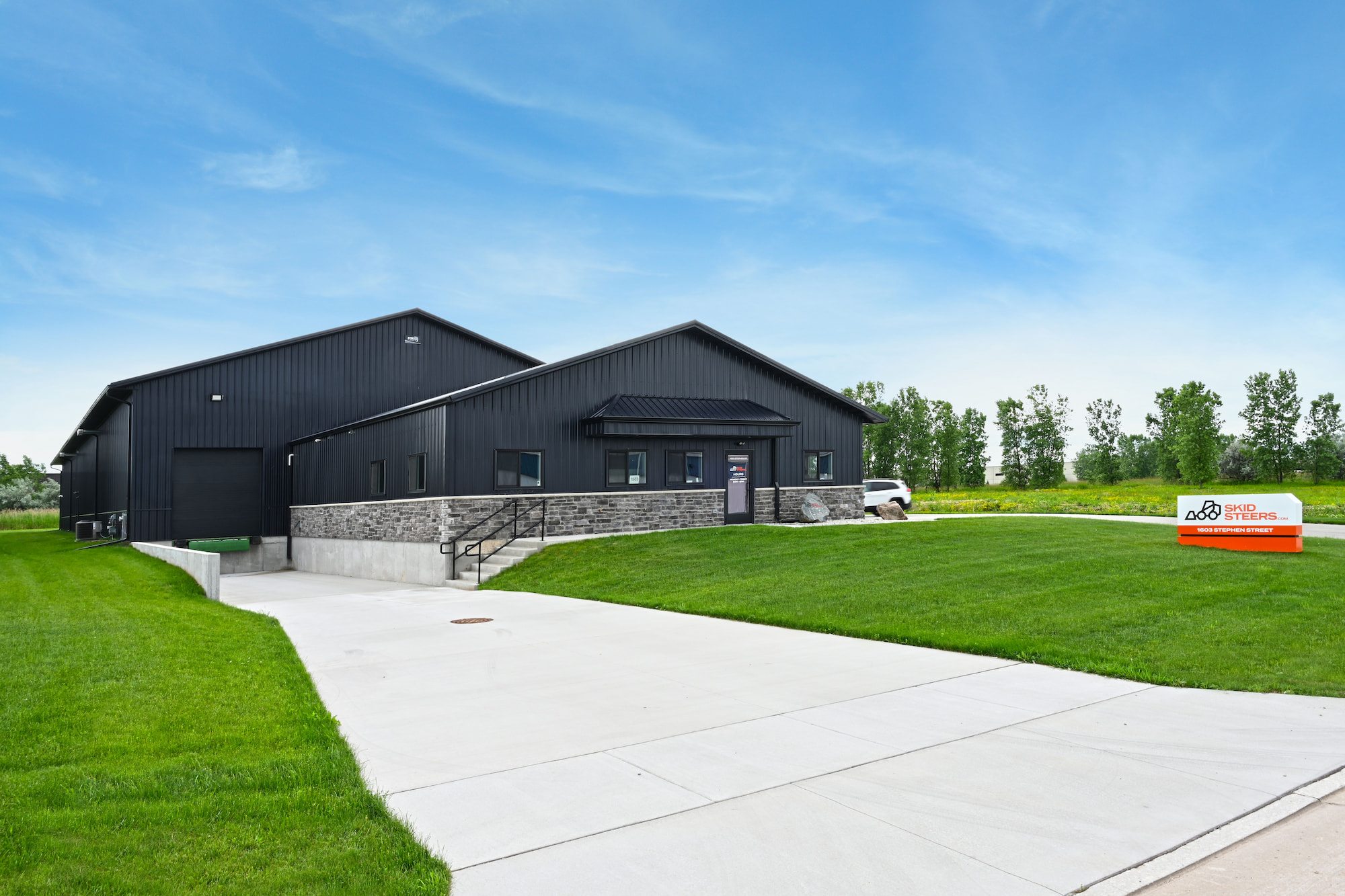 Front driveway view of SkidSteers.com custom black steel warehouse and office in Little Chute, WI by Fox Structures.