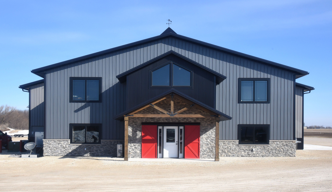 Front exterior of Forest Brook Farms, a gray office and storage building with black accents and red doors.
