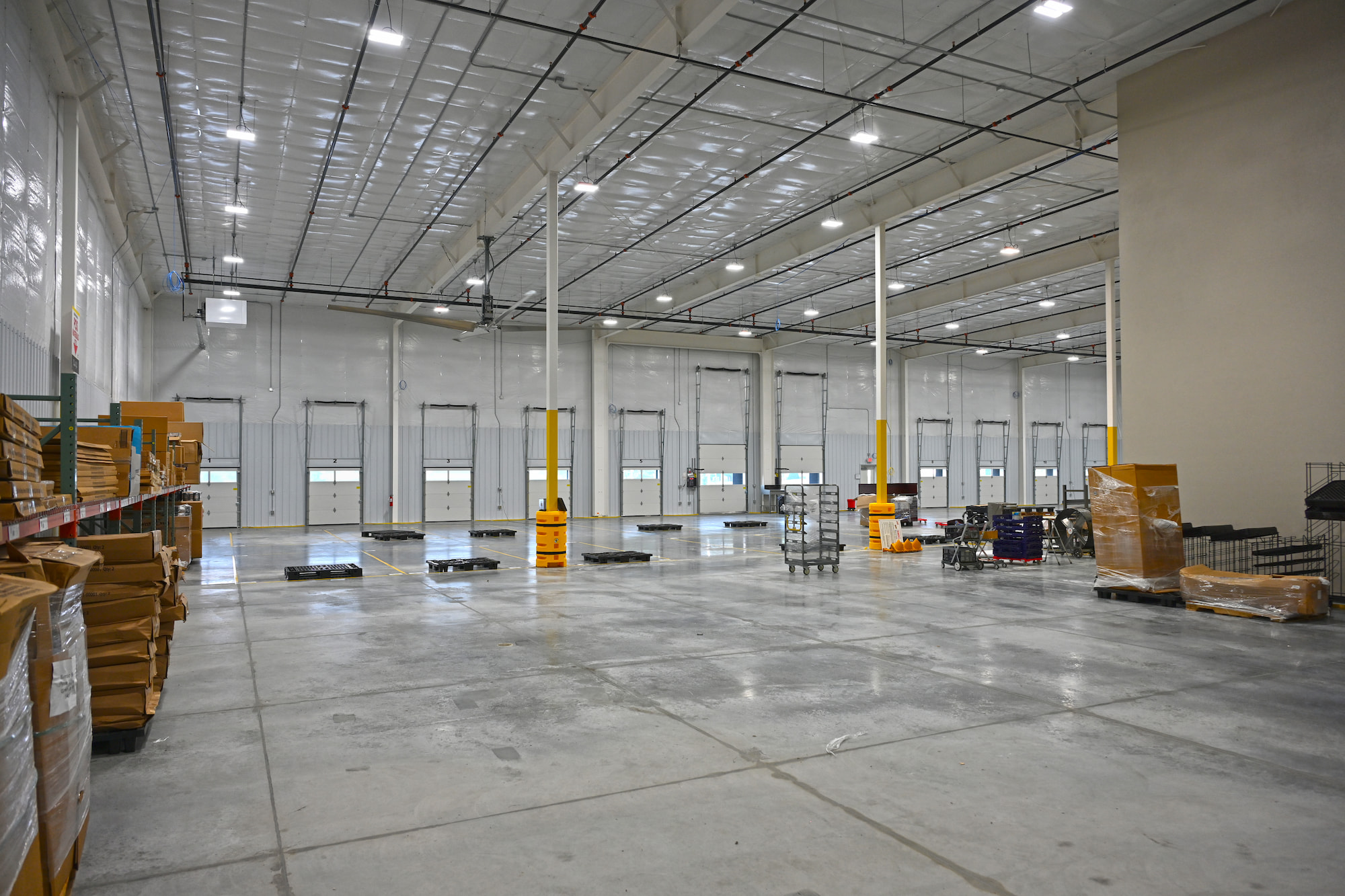 Interior of commercial warehouse in Kaukauna, WI with high ceilings, loading bays, and pallet storage areas.