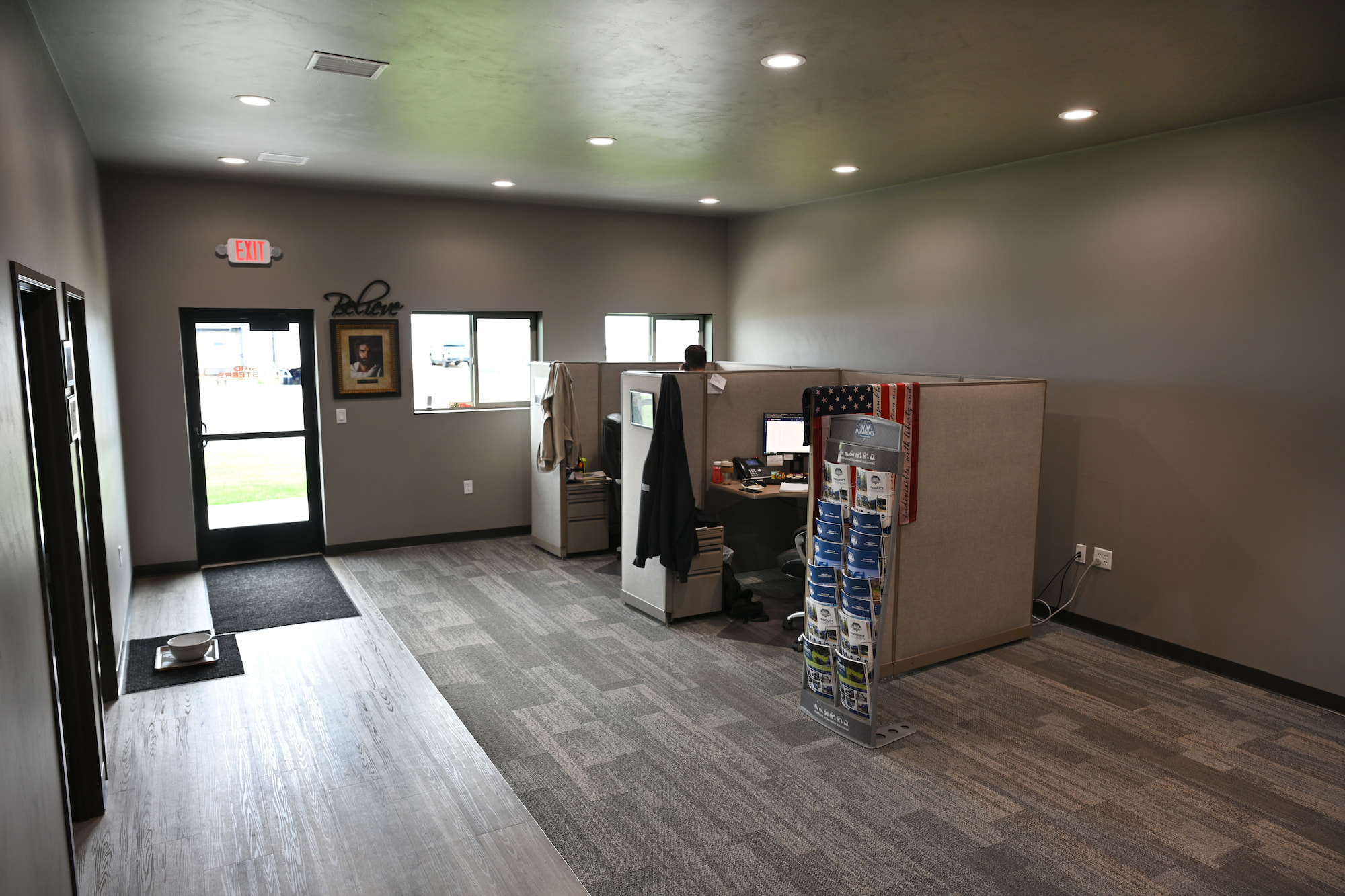 Employee workspace with cubicles and marketing displays at SkidSteers.com office in Little Chute, WI.
