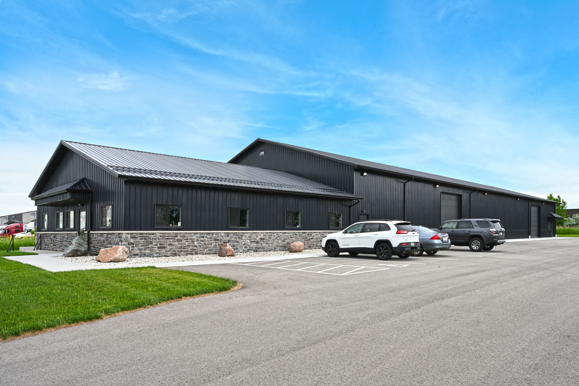 Side view of SkidSteers.com warehouse with employee parking area in Little Chute, WI steel building by Fox Structures.