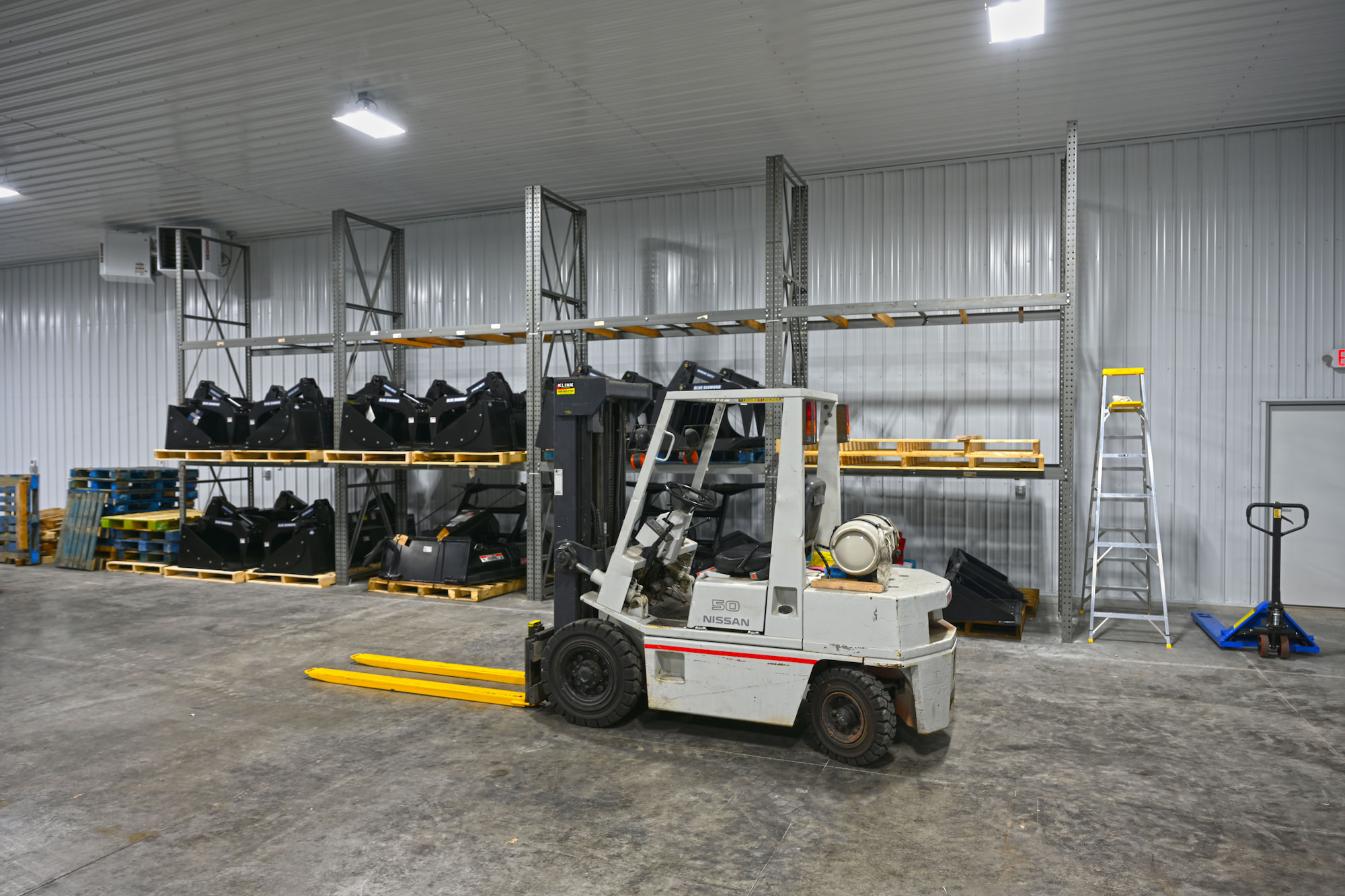 Nissan forklift and skid steer attachments stored on pallet racking inside SkidSteers.com warehouse.