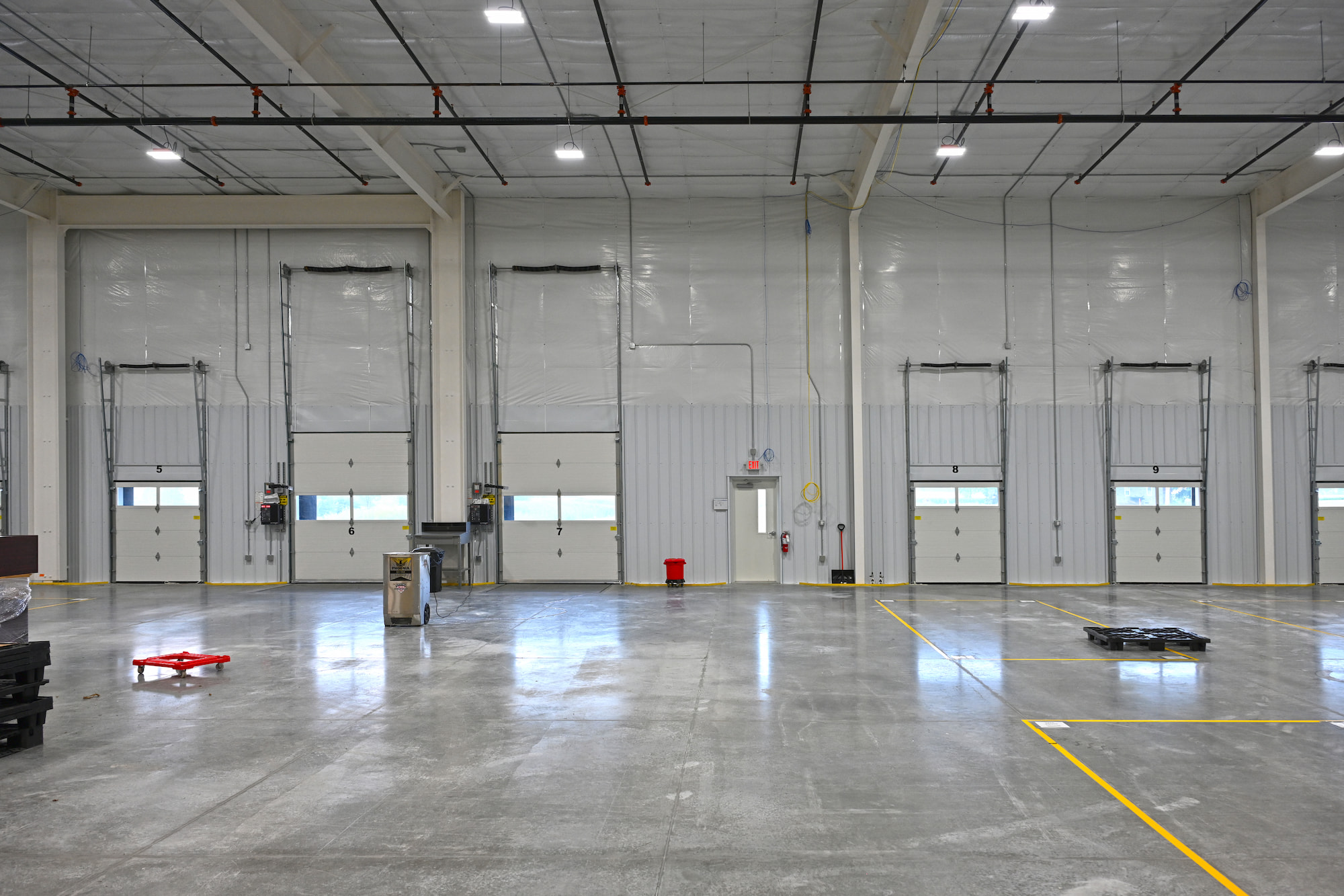 Warehouse interior in Kaukauna, WI showing multiple dock doors, polished concrete floor, and safety striping.