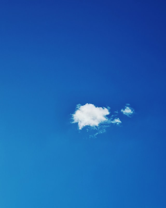 A single cloud in a deep blue sky.